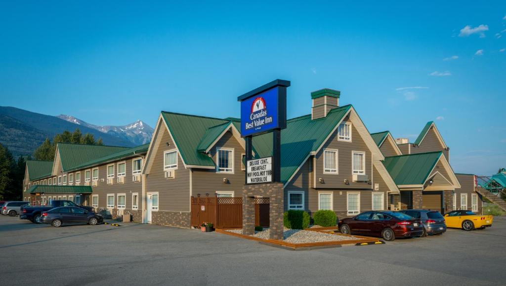 un gran edificio con coches estacionados en un estacionamiento en Canadas Best Value Inn Valemount, en Valemount