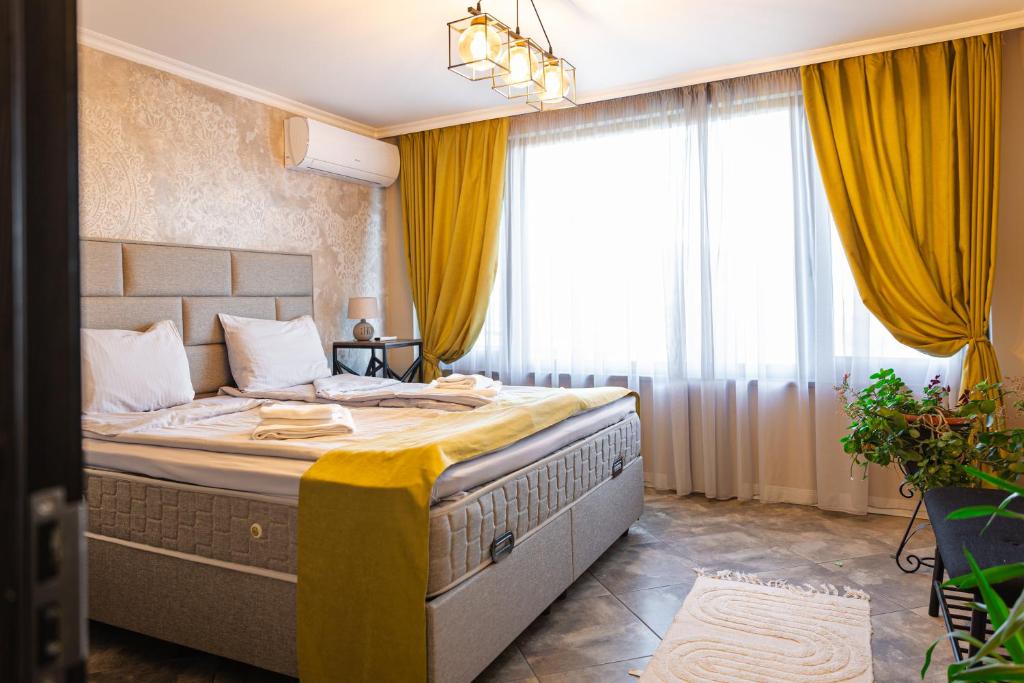 a bedroom with a large bed with yellow curtains at Dervent Apartment in Veliko Tŭrnovo