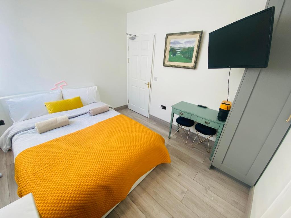 a bedroom with a bed with an orange blanket and a desk at CROKE PARK STUDIO in Dublin