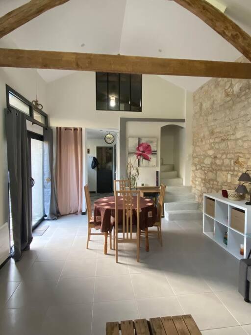 une salle à manger avec une table et un mur en pierre dans l'établissement Maison de charme - proche Futuroscope, à Montamisé