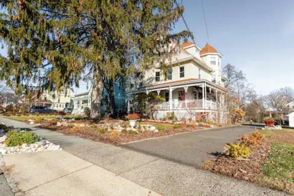 uma grande casa branca com uma árvore e uma rua em 3rd Floor Cozy Unique Apt em Montclair