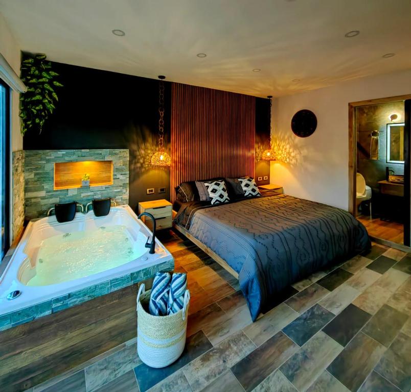 Schlafzimmer mit einem Bett und einer Badewanne in der Unterkunft Habitación Deluxe 1 con Jacuzzi a 20mt del parque in Salento