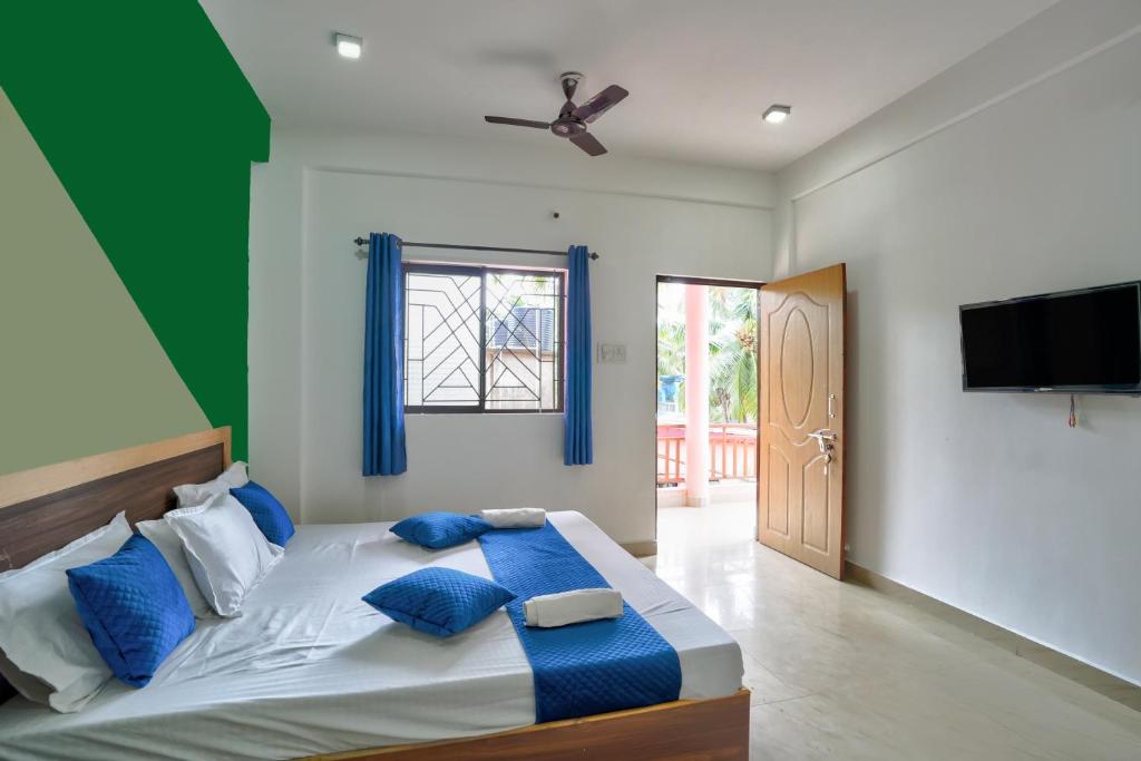 a bedroom with a large bed with blue pillows at Abbi's Nest Beach House Goa in Calangute