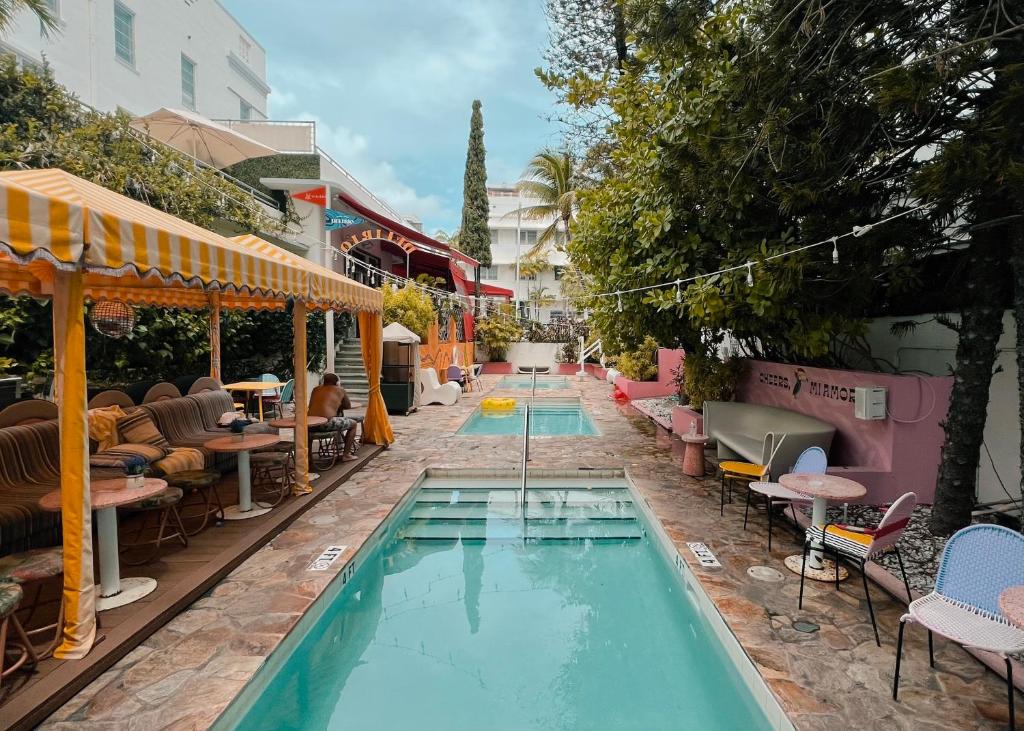 einen Pool mit Tischen und Stühlen neben einem Gebäude in der Unterkunft Viajero Miami in Miami Beach