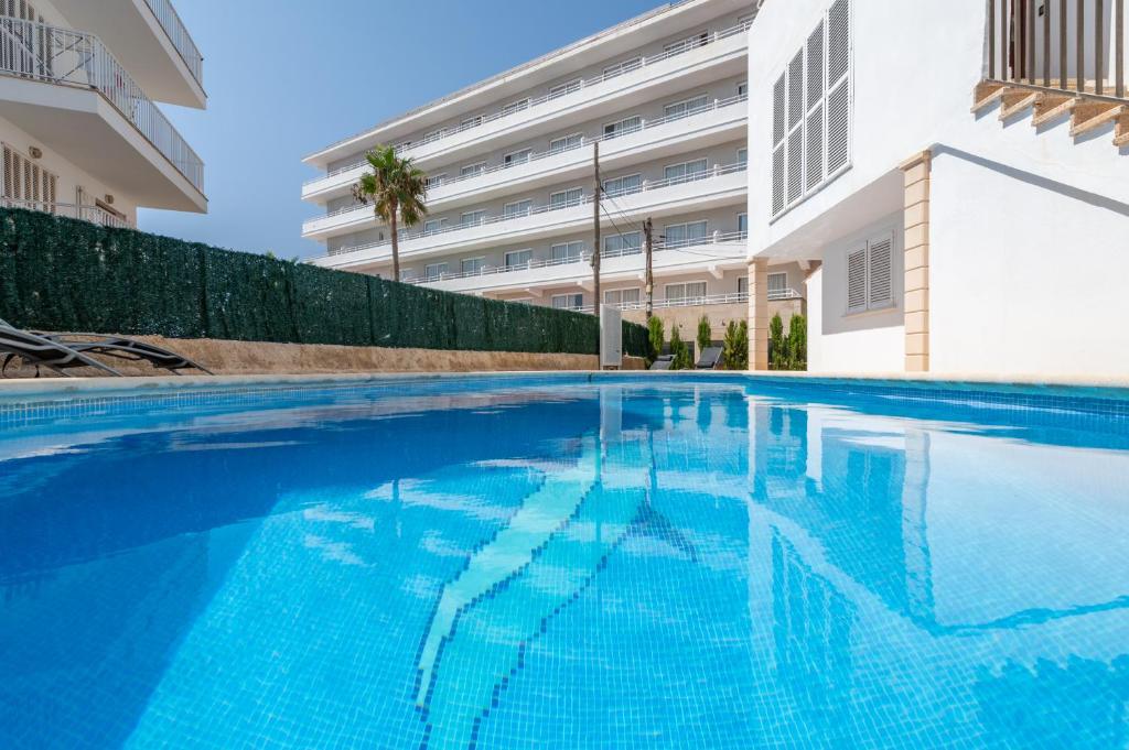 a swimming pool in front of a building at Apartamentos Marivent in Portocolom