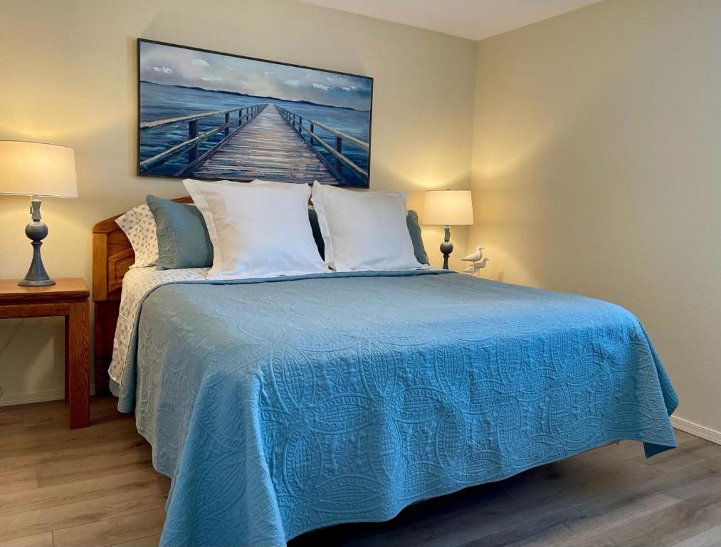 Un dormitorio con una cama azul con una pintura en la pared en Pasado Del Rio, Downtown getaway en Lake Havasu City
