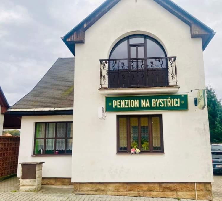 a white building with a balcony on top of it at Penzion na Bystřici in Miletín