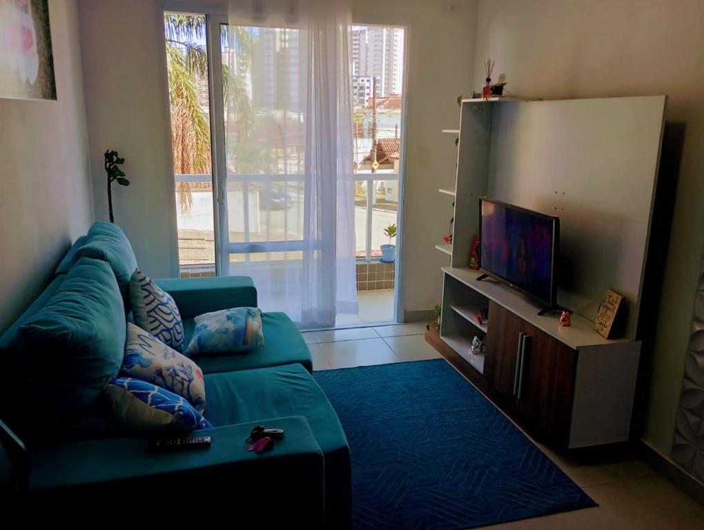 ein Wohnzimmer mit einem Sofa und einem Flachbild-TV in der Unterkunft Apartamento 2 quartos próximo da praia in Praia Grande