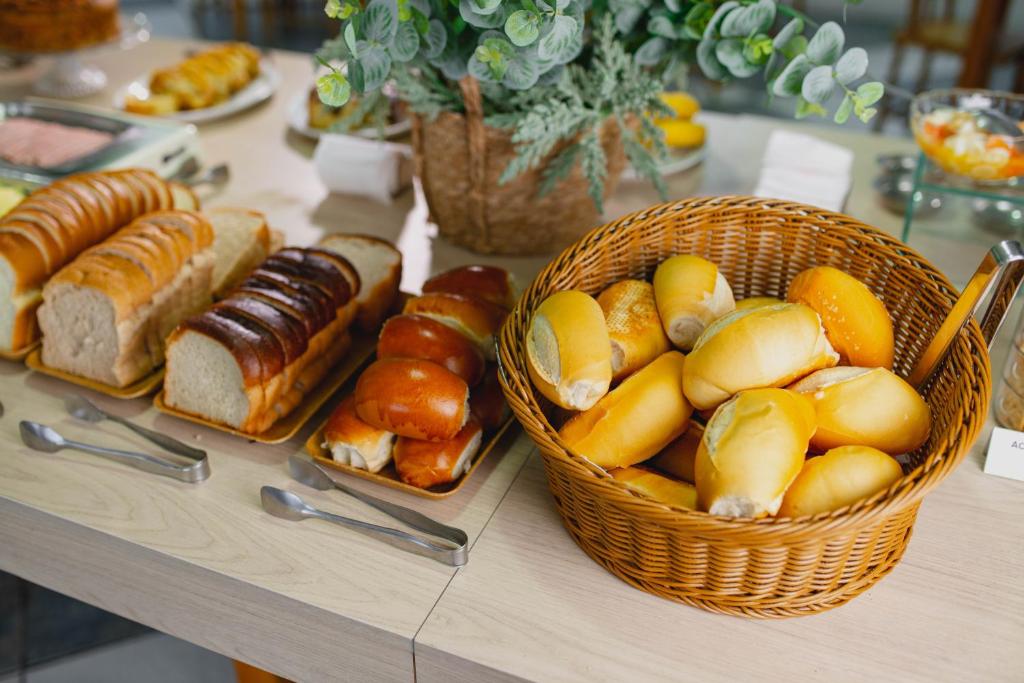 a table with a basket of bread and pastries at Ok Inn Hotel Floripa - SOB NOVA GESTÃO in Florianópolis