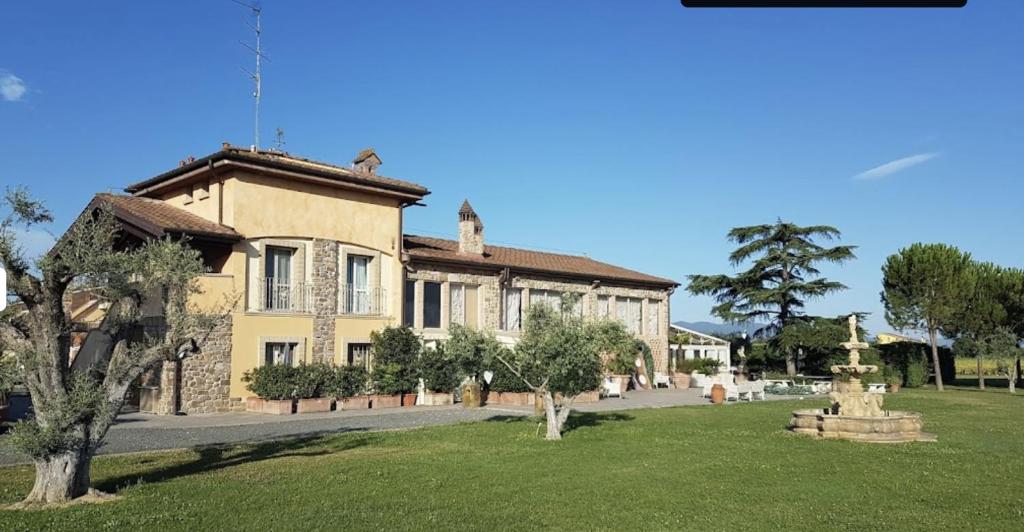 un grand bâtiment jaune avec des arbres devant lui dans l'établissement Agriturismo La Rugea - Le Spighe, à Prato