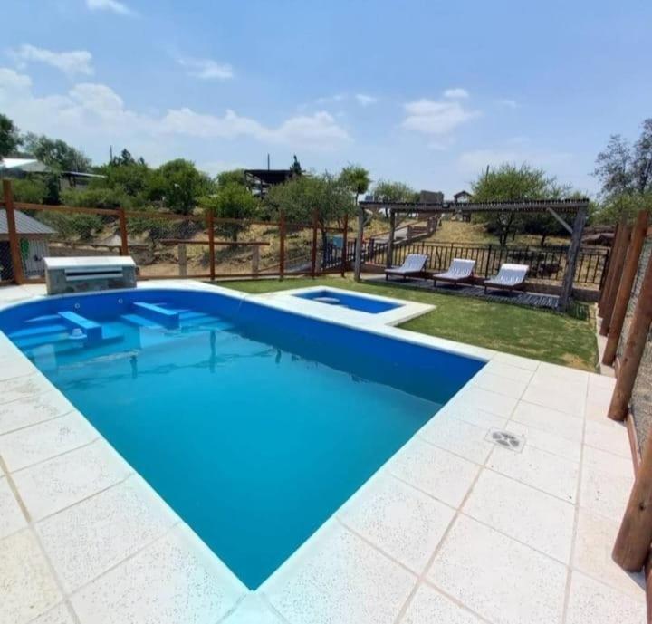 ein großer blauer Swimmingpool mit zwei Liegen in der Unterkunft Cabaña 2 in Cordoba