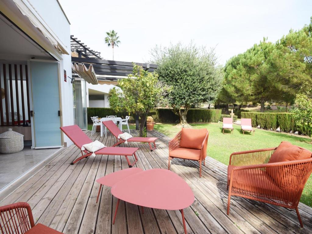 a deck with chairs and tables and a yard at Las Terrazas de Santa Clara in Marbella