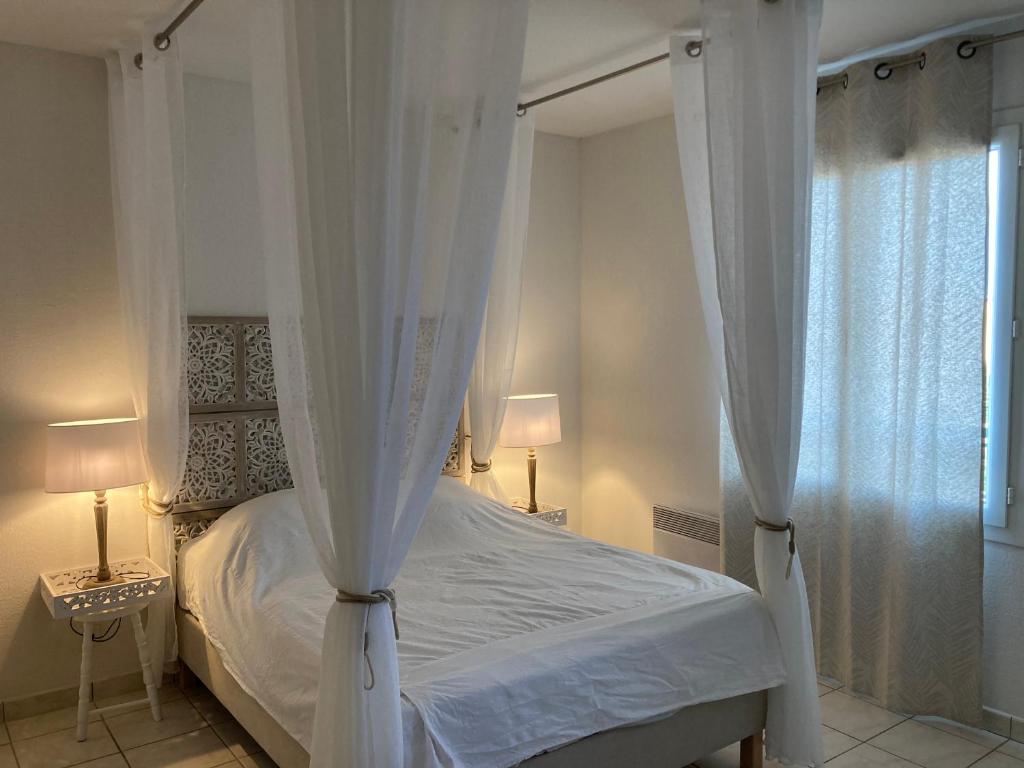 a bedroom with a canopy bed with white curtains at Villa climatisée calme avec piscine partagée Saint AYGULF/FREJUS in Saint-Aygulf