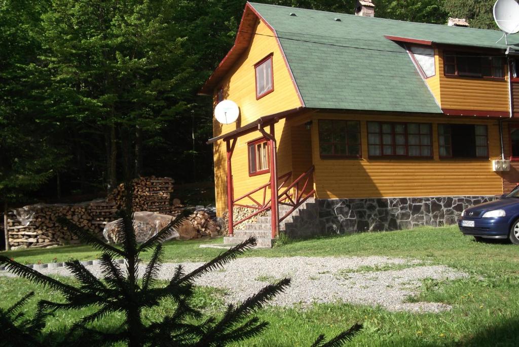 żółty dom z samochodem zaparkowanym przed nim w obiekcie Szilvia Vendégház w mieście Izvoare