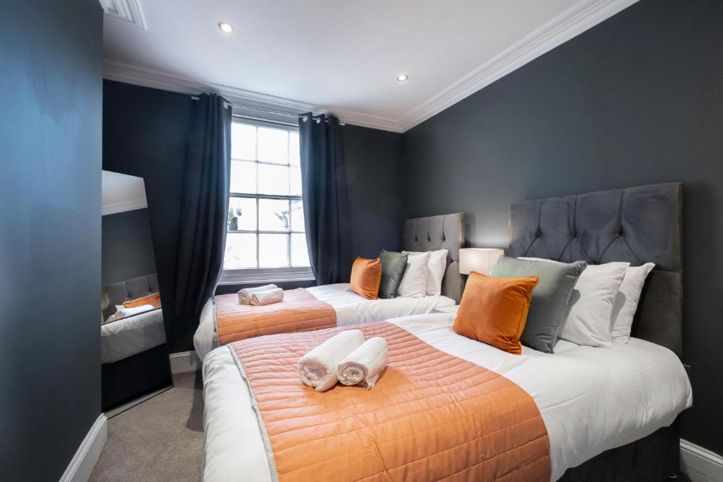 a bedroom with two beds with orange and gray at Stunning 4 Bedroom Home in Montpellier in Cheltenham