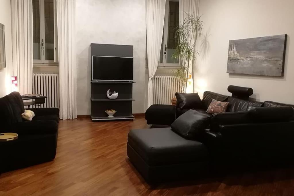 ein Wohnzimmer mit einem schwarzen Sofa und einem Flachbild-TV in der Unterkunft Appartamento Crisopoli in pieno centro a Parma in Parma