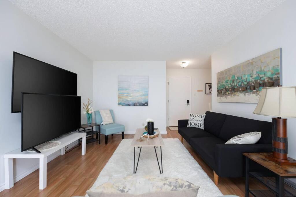 a living room with a black couch and a tv at Spacious 1BR with Parking and WiFi Near NLRHC in Fort McMurray