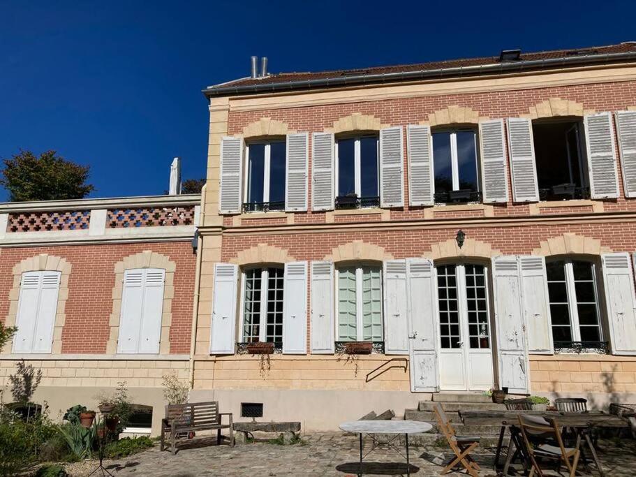 un bâtiment en briques avec des volets blancs et une table devant. dans l'établissement Très calme à côté du château, à Versailles
