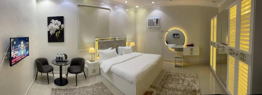 a bedroom with a white bed and a table and chairs at وحدات صروح الفاخرة in Al Madinah
