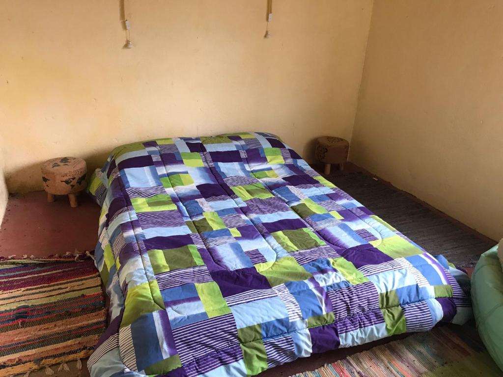 a bed in a room with a colorful quilt at El Albergue del Paso Polo (Quebrada de los Cuervos) in Isla Patrulla