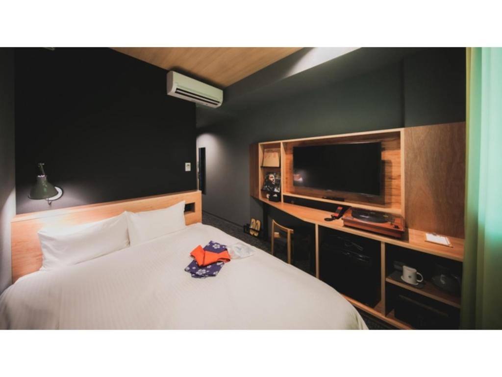 1 dormitorio con 1 cama blanca y TV de pantalla plana en dogo hakuro - Vacation STAY 80196v, en Matsuyama