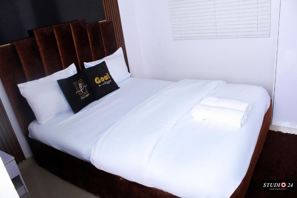 a white bed with two pillows on top of it at Daisies in Lekki