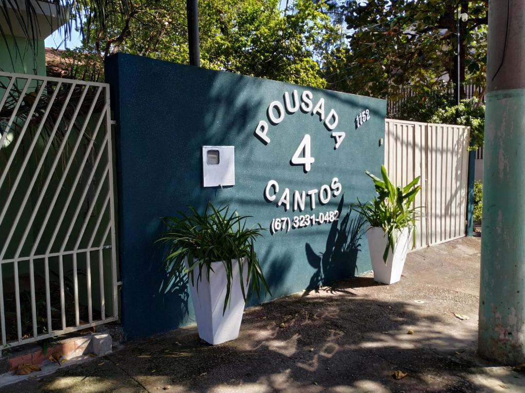 a blue wall with two potted plants next to a fence at Pousada 4 cantos in Corumbá