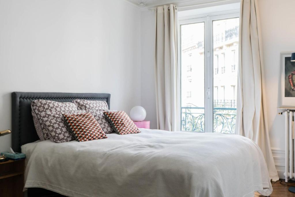 a bedroom with a bed with pillows and a window at Beautiful &amp; Bright Apartment Near Pigalle in Paris