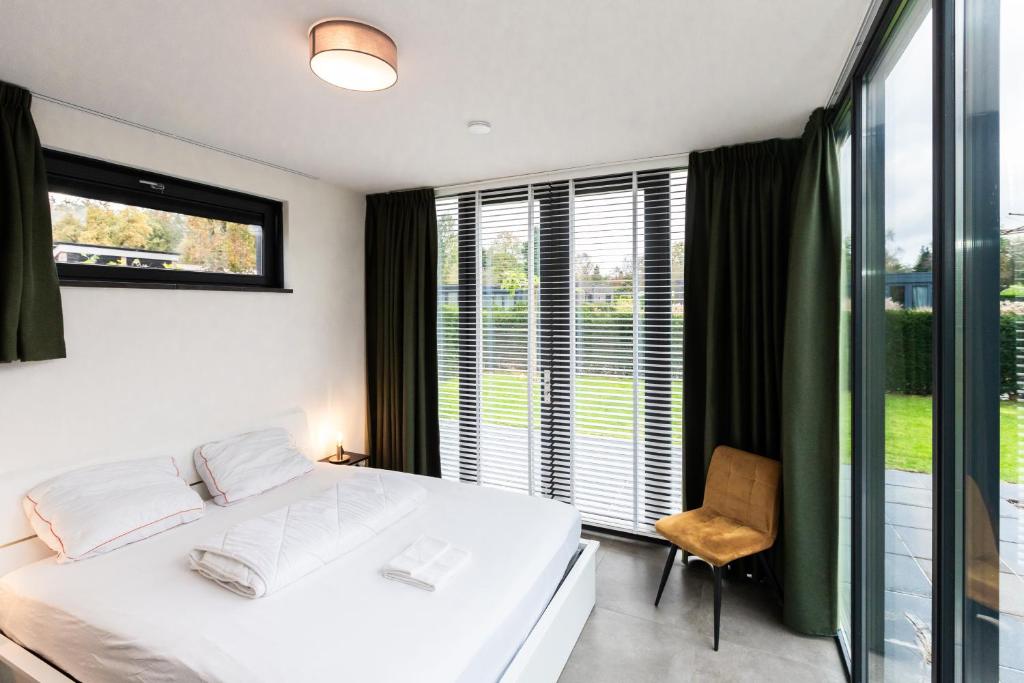 a bedroom with a white bed and a window at Wellness bungalow with Sauna in Ermelo