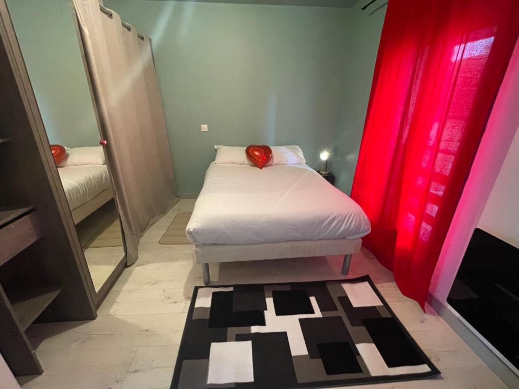 Kleines Zimmer mit einem Bett und roten Vorhängen in der Unterkunft Logementprivatif en famille à Disney in Montry