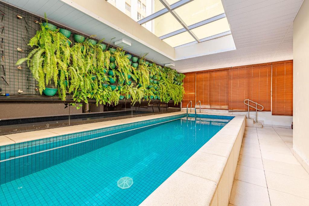 uma piscina com plantas penduradas por cima em FLAT CODE ACLIMAÇÃO - PISCINA - ACADEMIA - SAUNA - Pet e infantil em São Paulo
