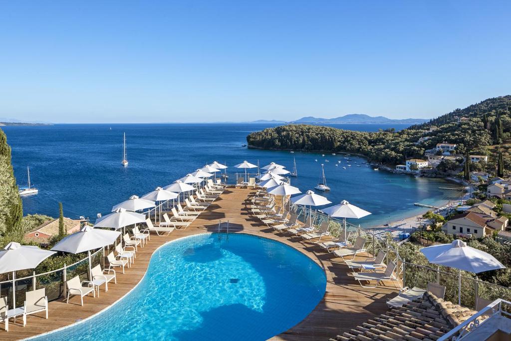 een zwembad met parasols en stoelen en een strand bij San Antonio Corfu Resort (Adults Only) in Kalámi