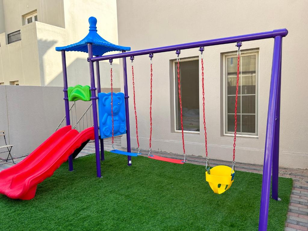 einen Spielplatz mit Rutsche und Schaukel in der Unterkunft فلة التاله مدينة الملك عبدالله الاقتصادية للعوائل فقط قريبه من النادى التأله استخدام النادى in King Abdullah Economic City