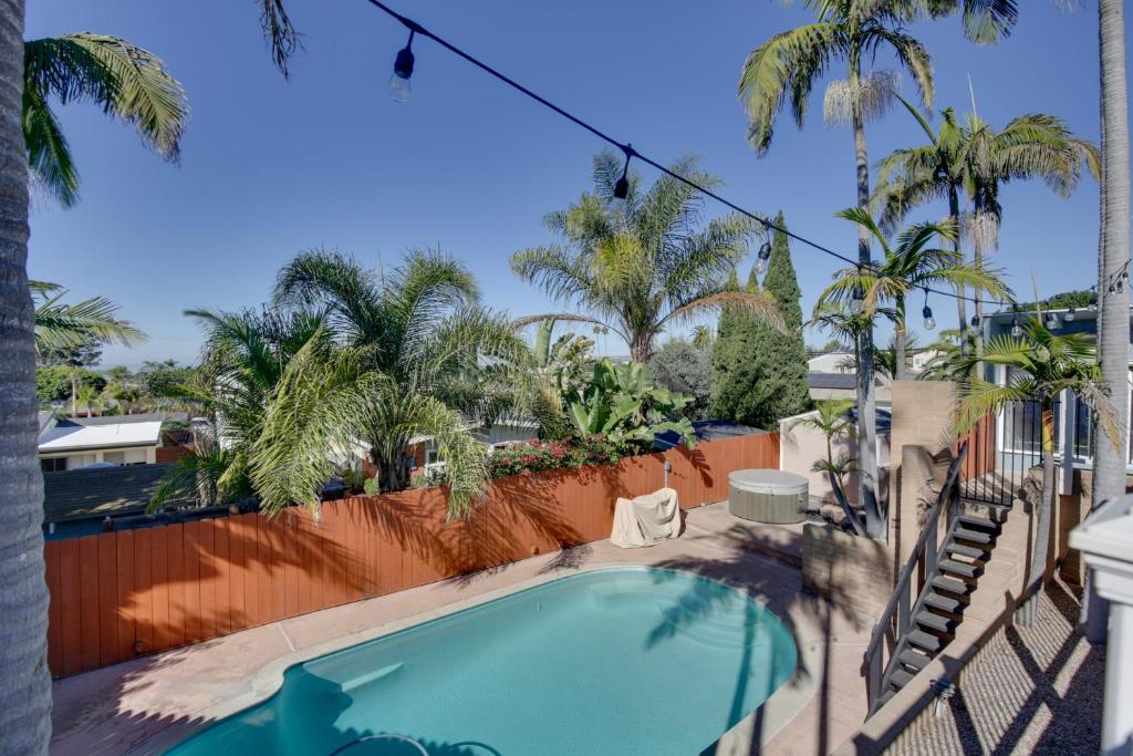 a swimming pool with a fence and palm trees at San Diego Home Private Outdoor Pool and Game Room! in San Diego