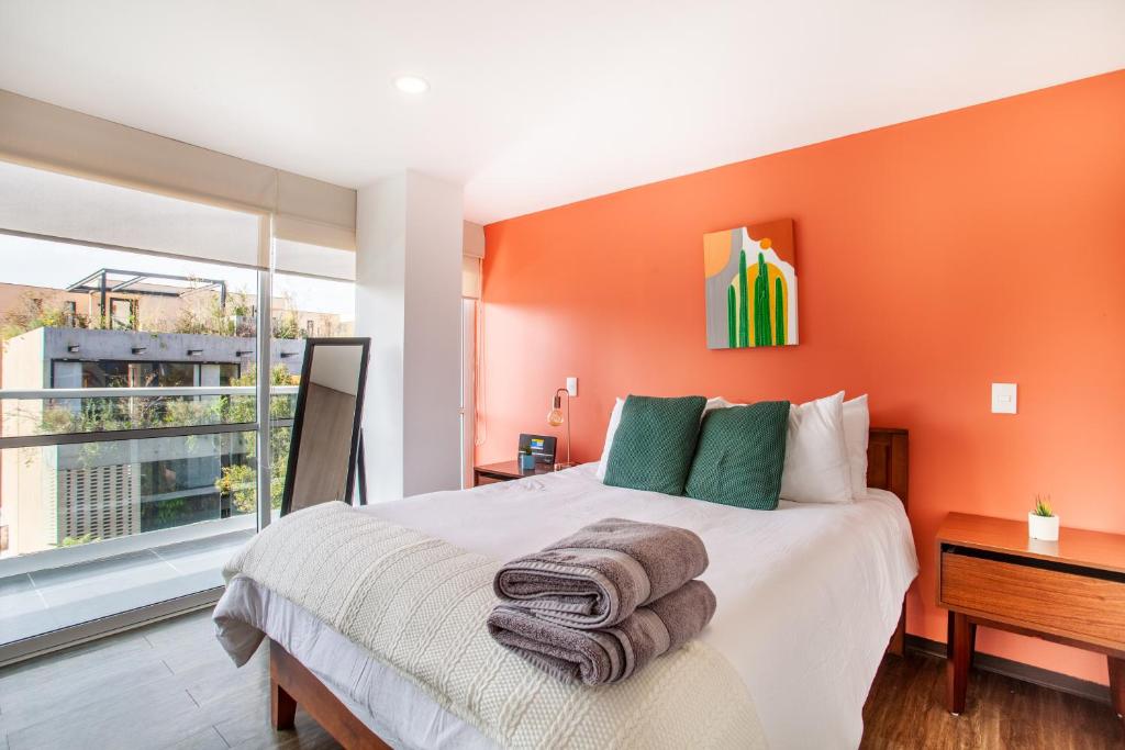 sypialnia z pomarańczowymi ścianami i łóżkiem z ręcznikami w obiekcie Moderno Mexicano 3BR/2BA 200Mbps w mieście Meksyk