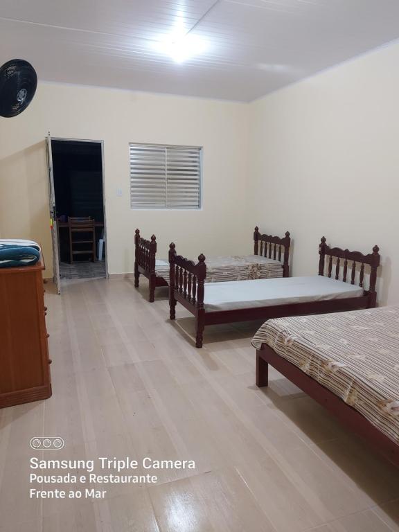 sypialnia z 2 łóżkami, stołem i oknem w obiekcie Pousada e Restaurante Frente ao Mar w mieście Cananéia