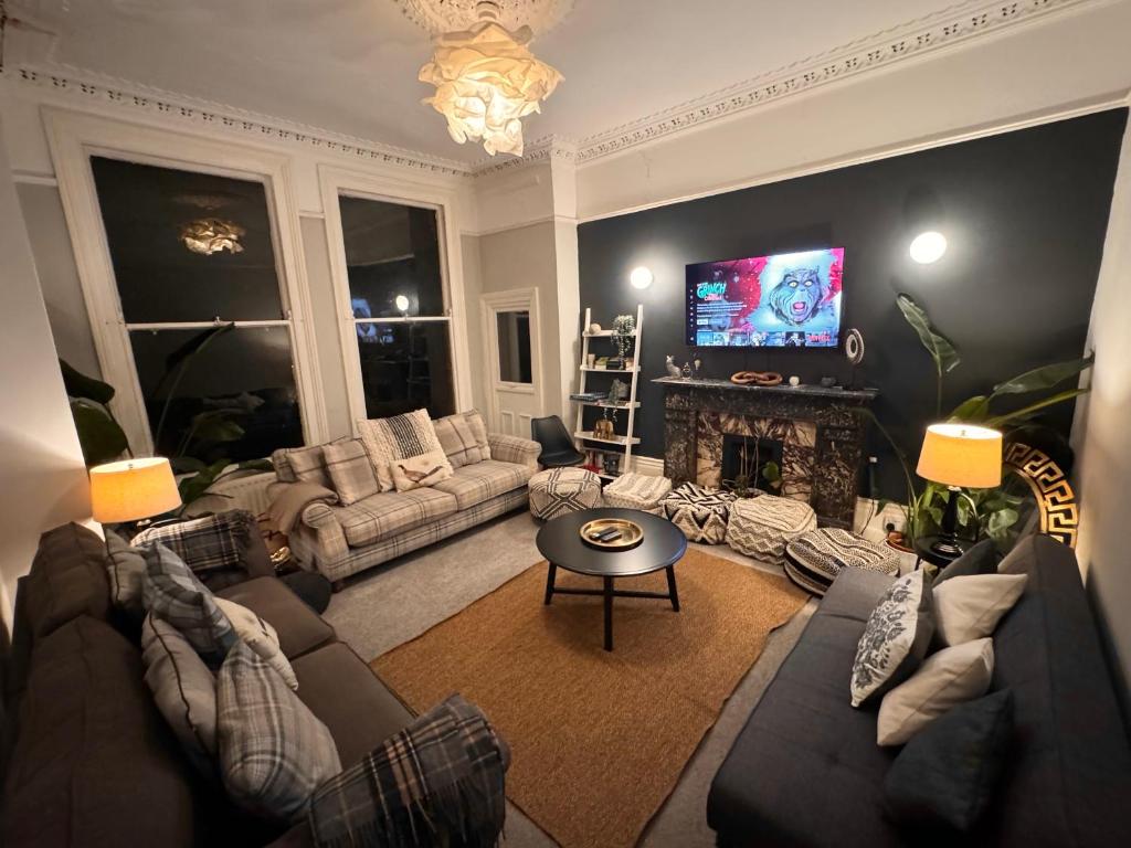 a living room with couches and a tv at Deluxe Huge Detached House with Parking, sleeps up to 30 people, 2m from Liverpool City Centre in Liverpool