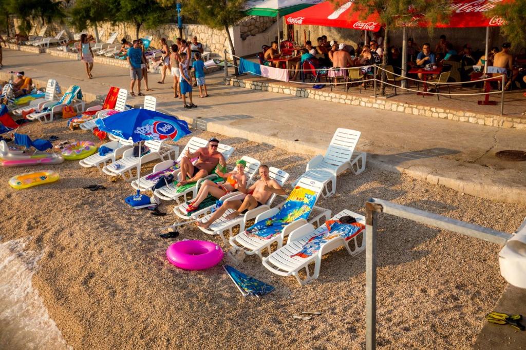 a group of people sitting in lawn chairs on the beach at Butique Maris in Komarna