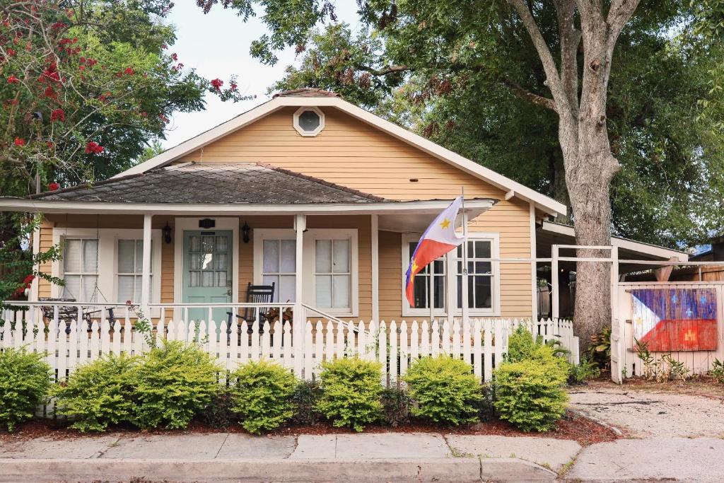 a yellow house with a white fence and a flag at Clinton Studio in Lafayette