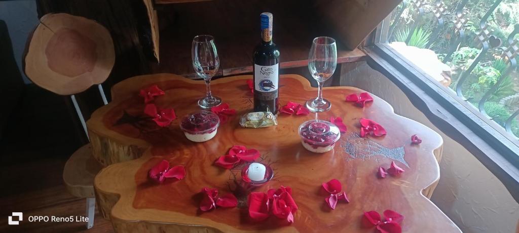 una mesa con copas de vino y rosas rojas. en Cabaña en el Arbol Picasso, en Bogotá