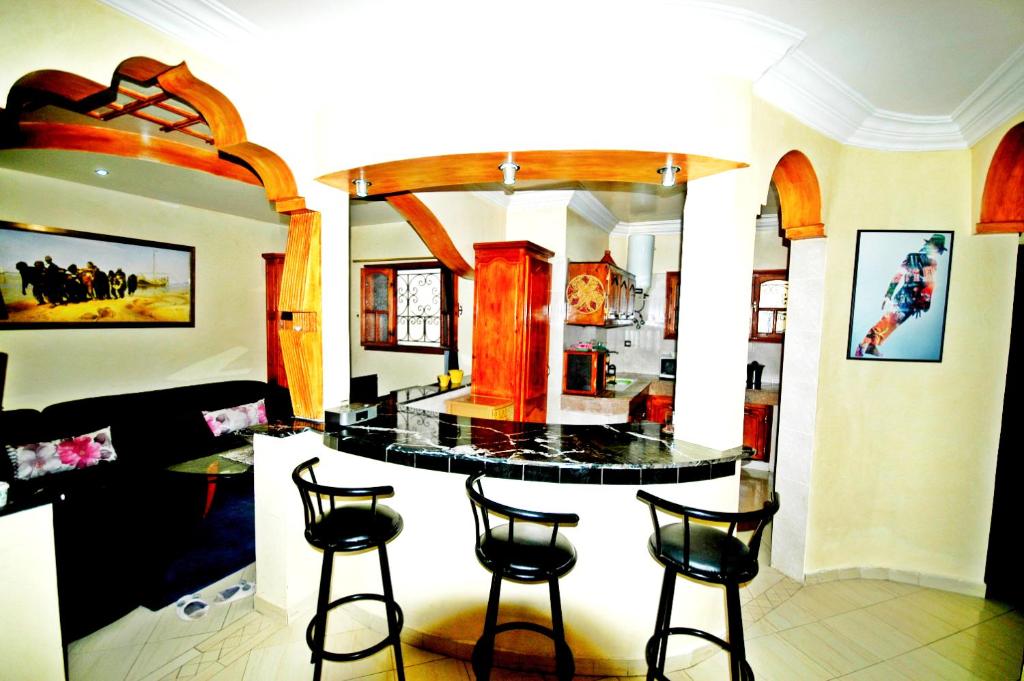 uma cozinha com uma ilha com quatro bancos de bar em Appartement Vintage à EL JADIDA rte Sidi Bouzid em El Jadida