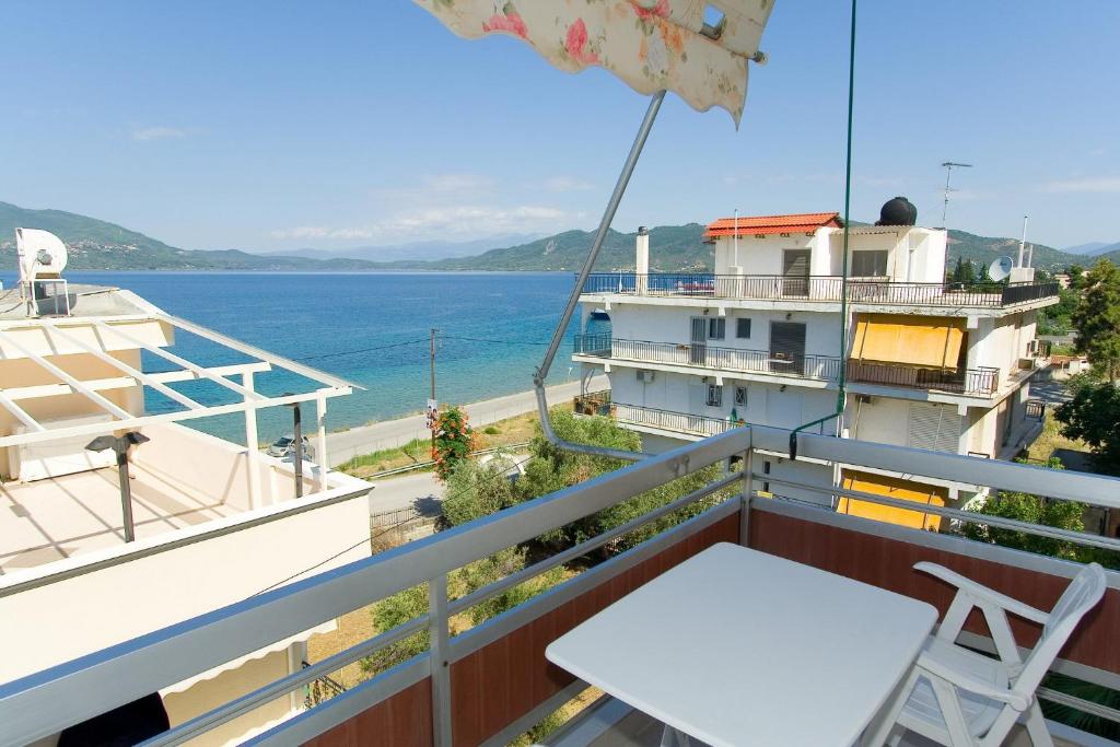 balcone con tavolo, sedie e vista sull'oceano di Valkaniotis Apartments a Loutra Edipsou