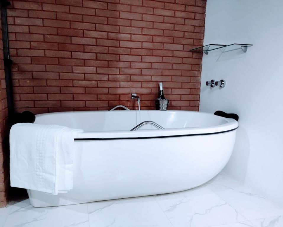 a white bath tub in front of a brick wall at Pousada Estância da Pinha in Santo Antônio do Pinhal