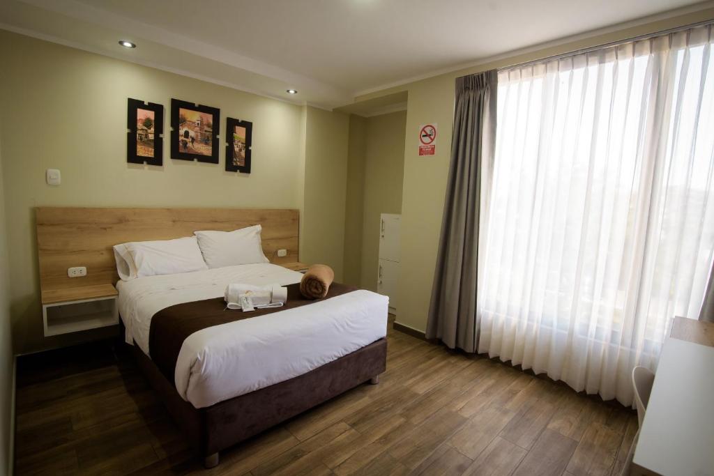 a bedroom with a bed and a large window at Hotel VILLA LUNA in Moquegua