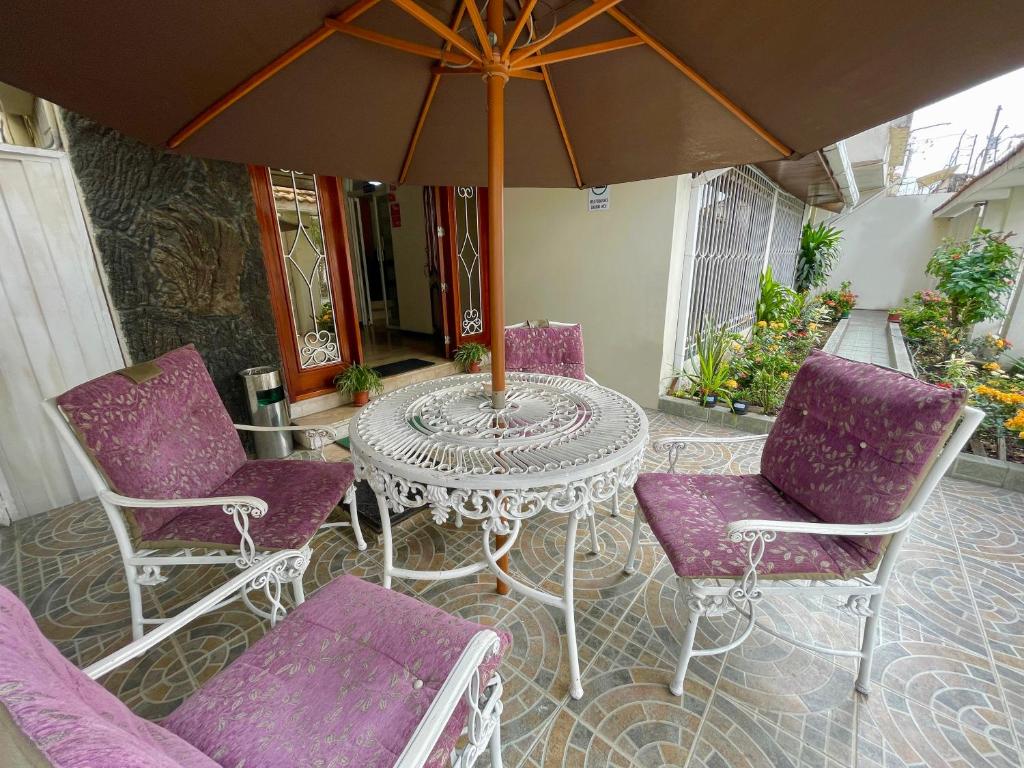 einen Tisch mit lila Stühlen und einem Sonnenschirm auf einer Terrasse in der Unterkunft Villa Garza Inn in Guayaquil