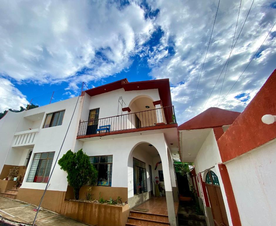 een wit huis met een rood dak en een balkon bij Casa EL Mundo in Oaxaca City