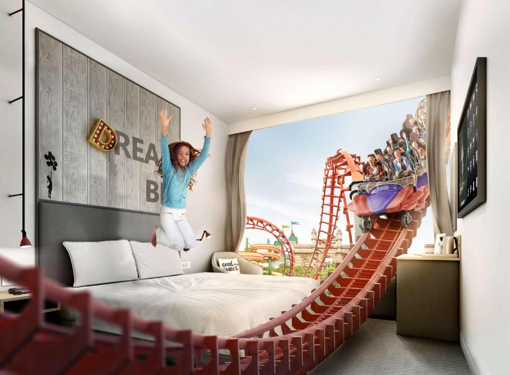 Rove At The Park في دبي: فتاة تقفز على سرير في غرفة مع الملاهي الدوارة