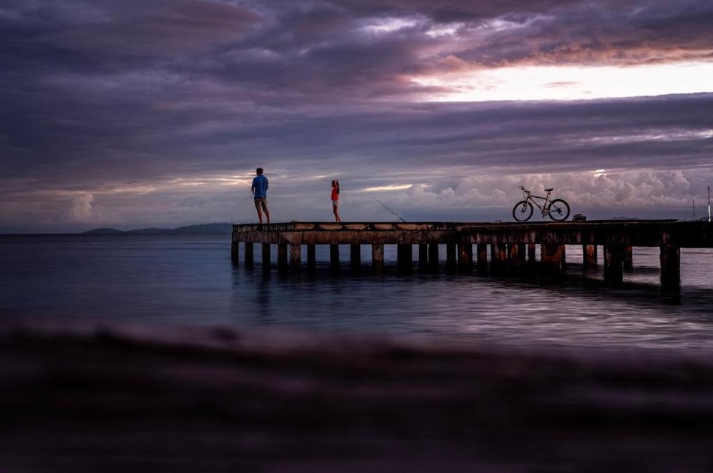 two people standing on a pier on the water at Hotel Tierra Verde Bed and Breakfast in Bocas del Toro
