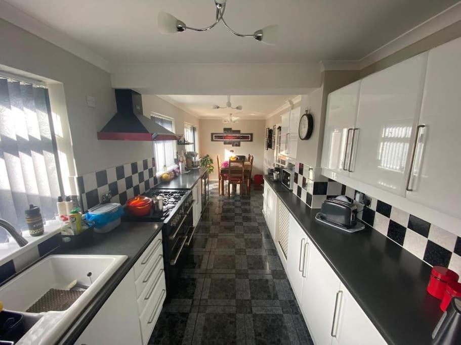 a kitchen with black counter tops and white cabinets at Spacious 5 bedroom, 2 Living Room, Games Room in Wolverhampton