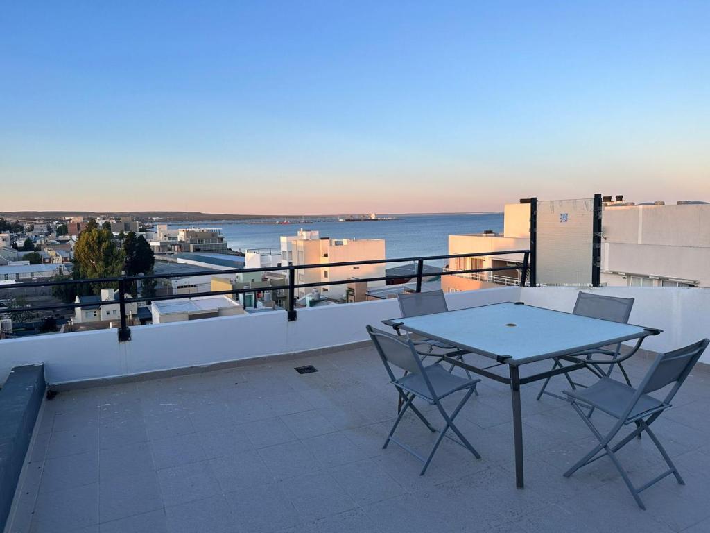 eine Terrasse mit Tisch und Stühlen auf einem Balkon in der Unterkunft Departamento frente al mar. Terraza y cochera privadas. Parrilla. in Puerto Madryn